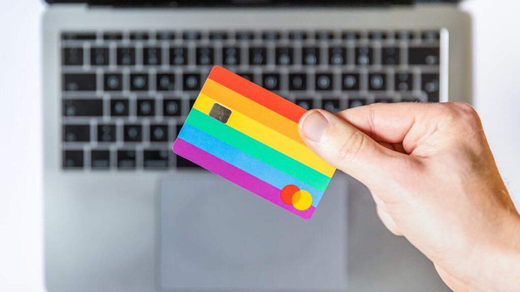 person holding rainbow credit card over laptop